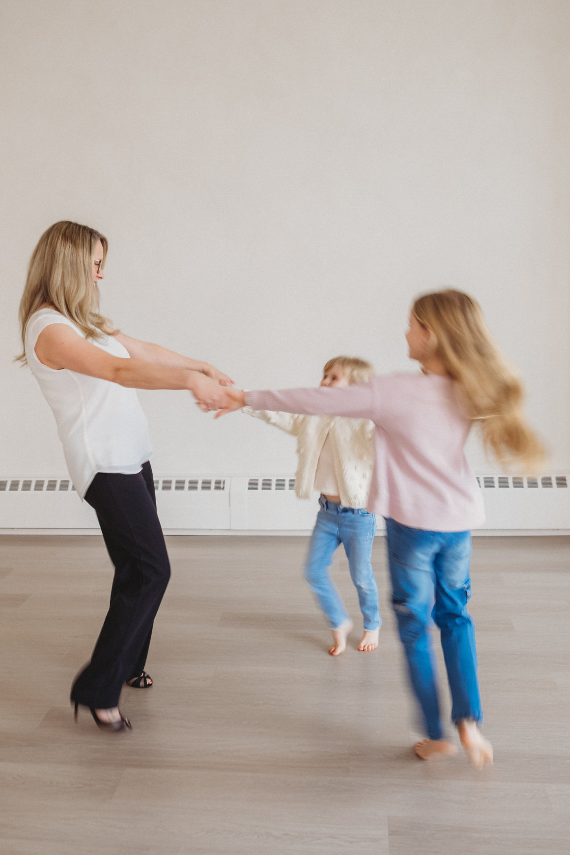 Sarah spinning and laughing with her two daughters, their movement softly blurred